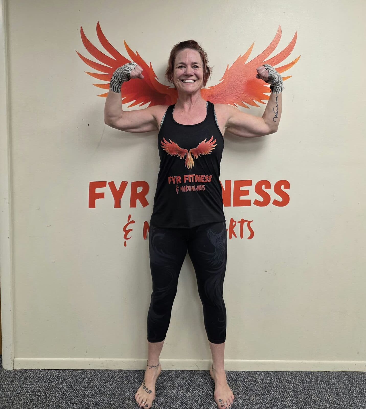 Member flexing in front of the FYR Fitness phoenix wings